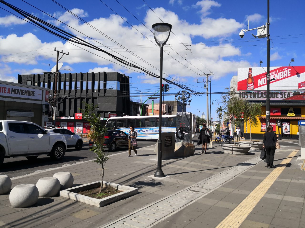 Microplaza en Barrio La California con escultura central, bancas esféricas y entorno urbano activo.