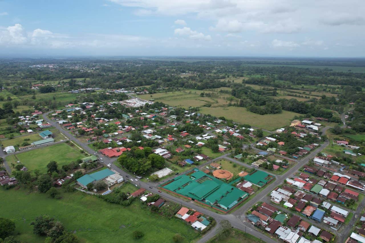 Vista del Parque Central Campo 5 con plaza, cancha cubierta y áreas verdes en la ruta a Tortuguero.