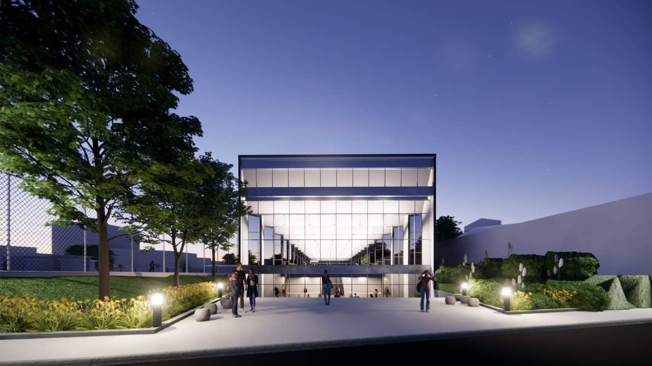 Piscinas Públicas de Grecia con volumen en diente de sierra y luz cenital Vista interior de la piscina semiolímpica con gradería y ventilación cruzada Acceso con plaza, escalera‑anfiteatro y vestíbulo de doble altura Fachada roja de Piscinas Públicas de Grecia iluminada de noche