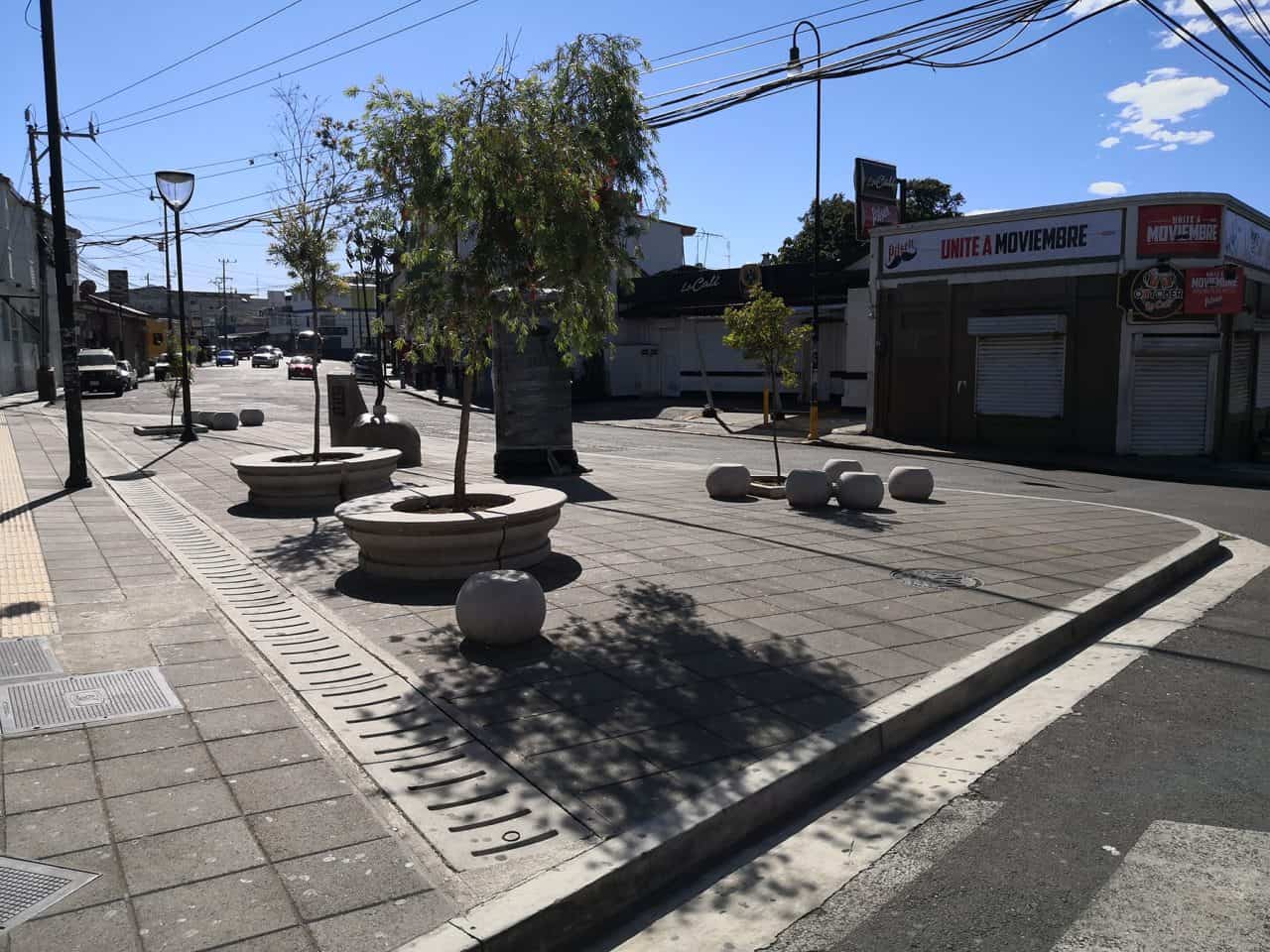 Microplaza en Barrio La California con escultura central, bancas esféricas y entorno urbano activo.