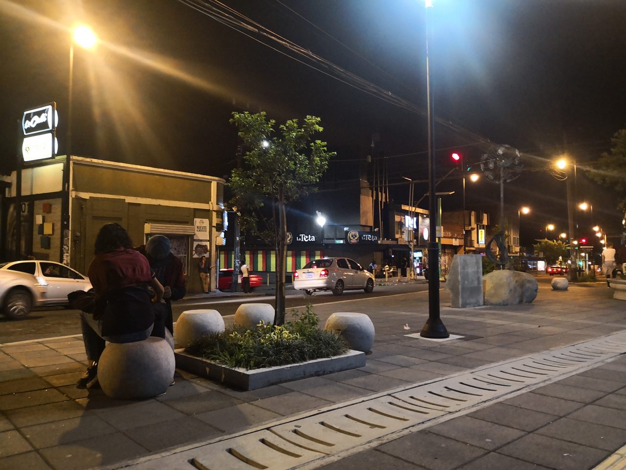 Microplaza en Barrio La California con escultura central, bancas esféricas y entorno urbano activo.