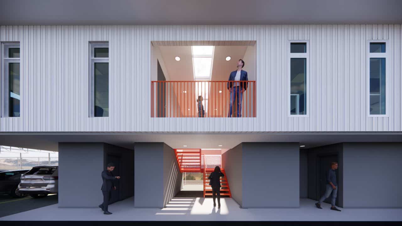 Vista del nuevo volumen en voladizo del plantel municipal de San Carlos con fachada sobria y escalera naranja.