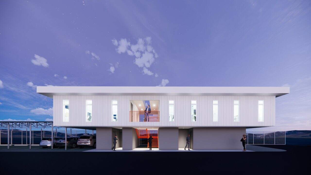 Vista del nuevo volumen en voladizo del plantel municipal de San Carlos con fachada sobria y escalera naranja.