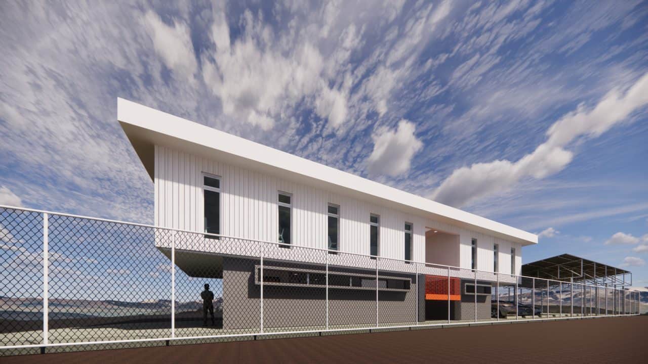 Vista del nuevo volumen en voladizo del plantel municipal de San Carlos con fachada sobria y escalera naranja.