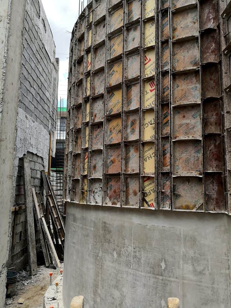 Municipalidad de Santa Ana en construcción, muro curvo de concreto expuesto recién desencofrado bajo la formaleta